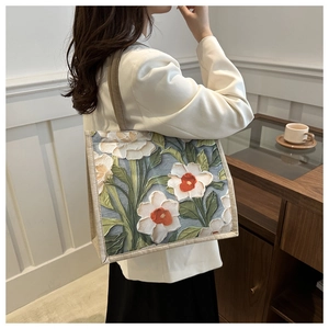 Close-up of 3D embossed floral tote bag with white and orange flowers on blue canvas