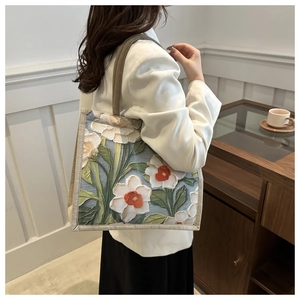 Détail du sac cabas bleu avec motifs floraux blancs en relief et anses tressées