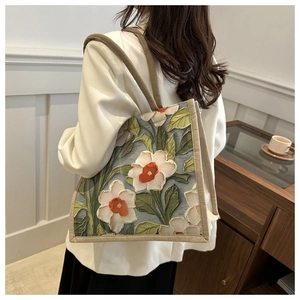 Detail of floral embossed texture and canvas strap on a blue tote bag over shoulder