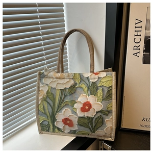 Close-up of floral tapestry tote bag featuring woven blue fabric and rope handles
