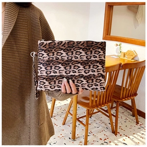 Detalle de bolso de mano con estampado de leopardo, cremallera y asa en una cafetería