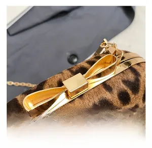 Close-up of golden bow-shaped metal clasp and leopard print fabric on luxury handbag
