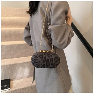 Detail van luipaardprint handtas met gouden striksluiting en metalen kettingriem luxe