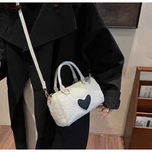 Close-up of a white plush faux fur mini Boston bag with a black heart patch and leather strap