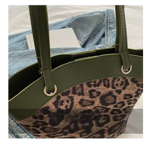 Close-up of leopard print tote bag featuring dark green leather trim and silver metal rings