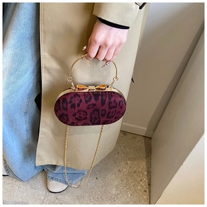 Detail of red leopard print evening clutch with gold bow clasp and metal chain handle