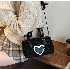 Detail of black faux shearling pillow bag with heart patch worn with casual outfit