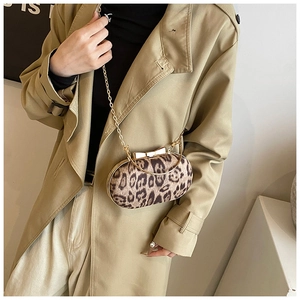 Detail of leopard print oval handbag featuring golden chain strap and bow clasp accessory