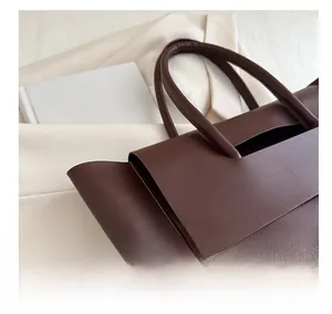 Macro detail of dark brown leather tote bag showing grainy texture and sturdy handles