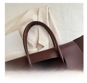 Close-up of comfortable thick handles and smooth brown faux leather of a tote bag