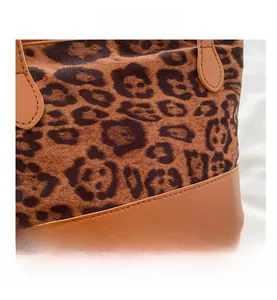 Detail shot of leopard print faux fur stitching and brown leather seams on a tote bag