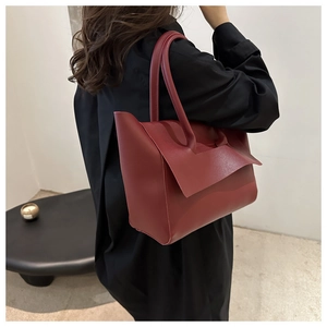 Dettaglio di borsa tote bordeaux vintage con patta asimmetrica su vestito nero