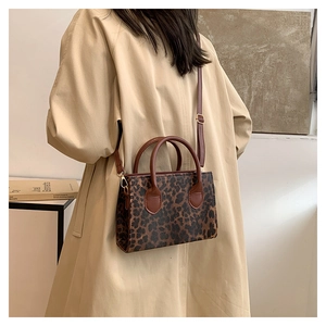 Detail of leopard print handbag with brown handles styled on a beige trench coat