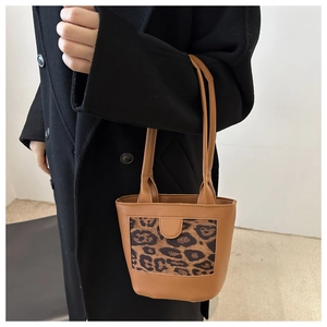 Detail of a brown leather mini tote bag featuring a stylish leopard print panel insert