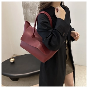Detailed view of burgundy minimalist shoulder bag with unique asymmetrical folded flap