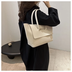 Dettaglio vista posteriore di una borsa a spalla minimalista bianco crema con due manici