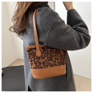 Detail view of the leopard print tote bag with brown leather handles and shoulder strap