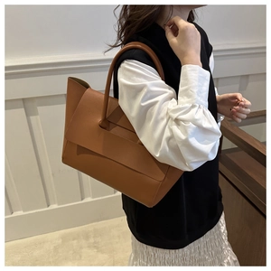 Borsa tote in pelle marrone con design unico del manico a patta e finitura opaca su modella