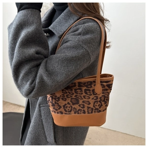 Detailed view of leopard print tote bag with brown leather straps worn over the shoulder