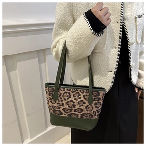Detailed view of leopard print and olive green tote bag worn with a white textured coat