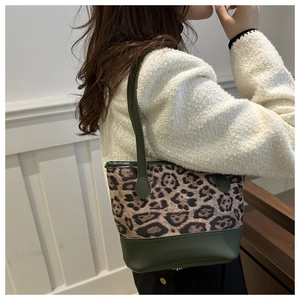 Leopard print tote bag with green leather straps shown on model from a side-rear view