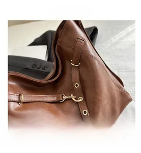 Close-up of vintage brown leather tote bag with gold metal hardware and fine texture