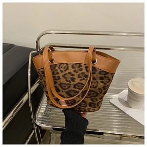 Close-up of leopard print bucket bag with brown leather straps and silver ring hardware