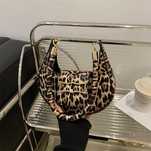 Borsa hobo leopardata con fibbia dorata su un elegante espositore d'interni