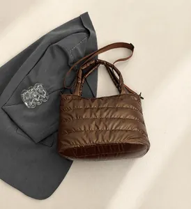 Detail view of the quilted brown puffer bag showing the soft texture and stitching