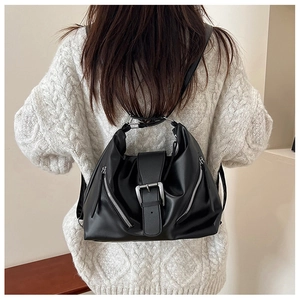 Detalle de bolso tote vintage negro con hebillas plateadas sobre un jersey de punto