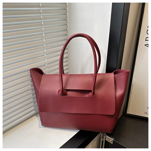 Detail view of burgundy leather tote bag with elegant flap cover and slim shoulder handles
