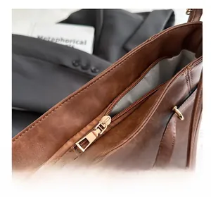 Detail of a smooth golden metal zipper on a premium brown faux leather tote bag