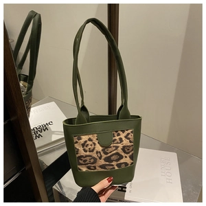 Detail view of dark green leather tote featuring a stylish leopard print panel and thin straps
