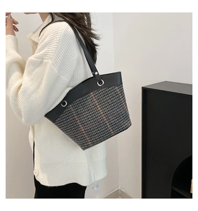 Détail d'un sac cabas à motif pied-de-poule avec bordure en cuir noir et boucle argentée