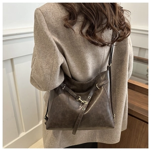 Close-up of a vintage dark brown leather tote bag with gold metal hardware on model