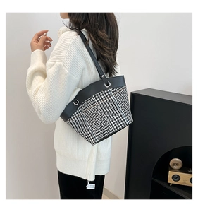 Mannequin portant un sac seau pied-de-poule noir et blanc avec bandoulière en cuir