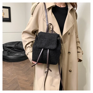 Sac à dos noir en polaire avec cordon, porté par un mannequin en trench beige