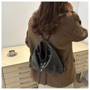 Detail of minimalist black leather tote bag showing fine hardware and adjustable strap