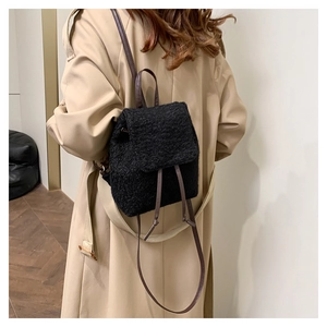 Détail d'un sac à dos en laine noire avec sangles en cuir marron et fermeture à cordon