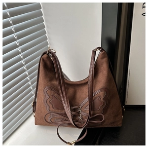 Dettaglio borsa tote marrone con toppa a fiocco ed elementi di allacciatura vintage