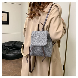 Vue détaillée du sac à dos en tweed gris avec rabat à cordon et lanières en cuir