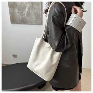 Vue détaillée du grand sac fourre-tout crème en daim porté avec une veste en cuir marron