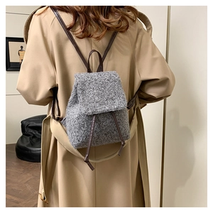 Detail view of a grey wool tweed mini backpack with brown leather straps on a model