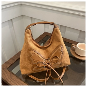 Dettaglio della borsa in pelle scamosciata marrone con patchwork a fiocco e lacci decorativi
