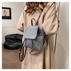 Sac à dos en tweed gris avec bretelles marron, porté par un mannequin en intérieur moderne