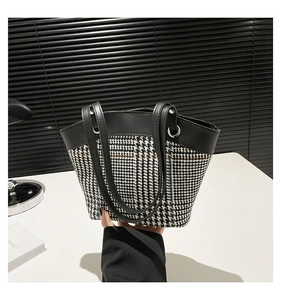 Détail du sac cabas en pied-de-poule avec anses en cuir noir et anneaux métalliques