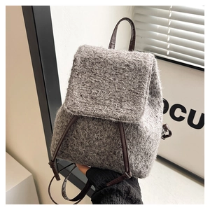 Close-up detail of grey fleece texture and brown leather straps on stylish backpack