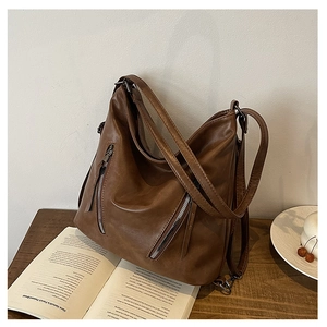 Détail d'un grand sac cabas en cuir marron avec fermetures éclair sur une table