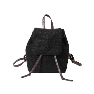 Minimalist black wool backpack with brown leather straps and gold hardware for winter