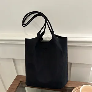 Sac seau minimaliste en daim noir avec double bandoulière sur présentoir en bois